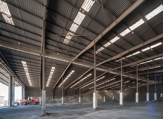 Covered bulk warehouse with cargo stockpiles and loading equipment